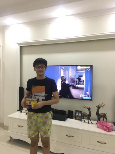 Un ragazzo in piedi davanti a una TV con una scatola di Happy House 1 a Hanoi