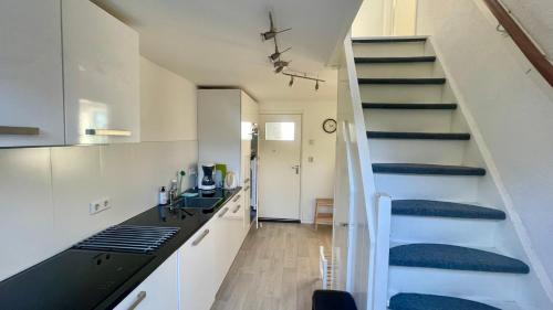 een kamer met een trap en een keuken met een bureau bij Strandhuis Everts in Egmond aan Zee