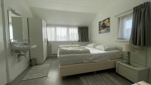 Habitación blanca con cama y lavabo en Strandhuis Everts, en Egmond aan Zee