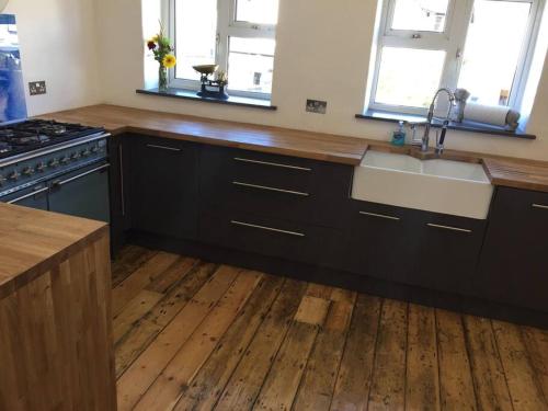 a kitchen with black cabinets and a wooden floor at Huge 7 bed hse for large groups close by the beach in Bude