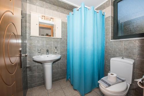 bagno con tenda doccia blu e servizi igienici di Magnolia Apartments and Studios a Falasarna