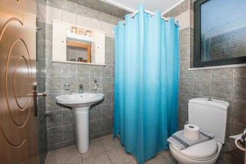 a bathroom with a blue shower curtain and a toilet at Magnolia Apartments and Studios in Falasarna