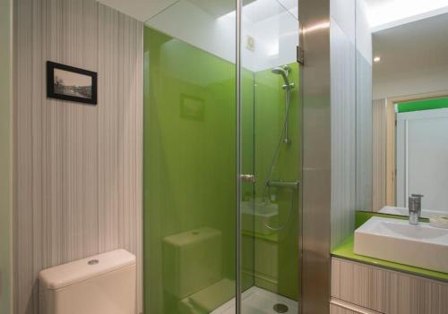 a green bathroom with a sink and a shower at Dunas Flat in Lavra
