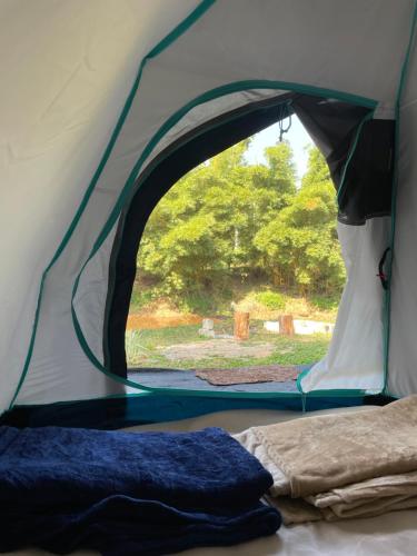 a tent with the door open and a bed in it at Byrahalli Bliss riverside camping in Sakleshpur