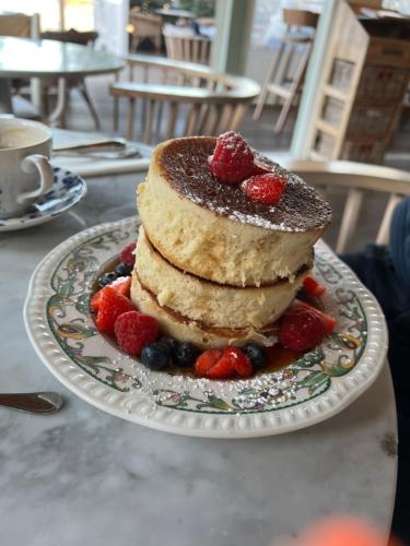 une pile de crêpes sur une plaque avec des fraises et des myrtilles dans l'établissement A La Plage et Au Soleil de St Palais sur Mer, à Saint-Palais-sur-Mer