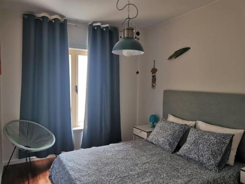a bedroom with blue curtains and a bed and a window at Dunas Flat in Lavra