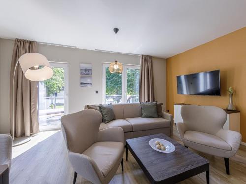 ein Wohnzimmer mit einem Sofa, Stühlen und einem TV in der Unterkunft Ferienwohnung Seesinn in Wustrow