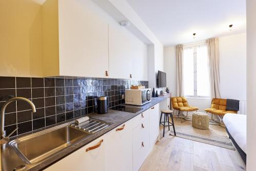 une cuisine avec des armoires blanches et un évier dans l'établissement Le Nid - appartements Bordeaux Centre, à Bordeaux