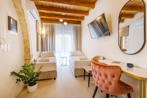 a room with two beds and a table and a mirror at Casa Del Balsamo in Rethymno Town