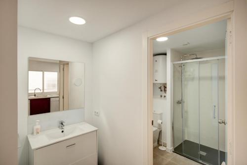 a white bathroom with a sink and a shower at Beds & Breaks - Marina Beach in Valencia
