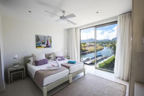 een slaapkamer met een bed en een groot raam bij West Coast Marina in Rivière Noire
