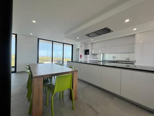 a large kitchen with a wooden table and yellow chairs at Luxury villas with heated pool & panoramic ocean & valley views in São Martinho do Porto