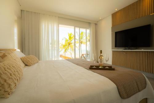 a bedroom with a large bed with a flat screen tv at Village Someday in Arraial d'Ajuda