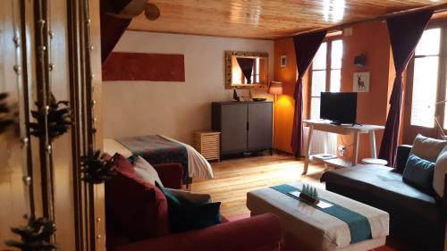 a living room with a bed and a couch and a television at À Deux Pas ... in Briançon