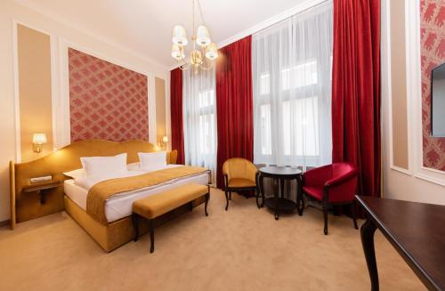 a hotel room with a bed and a table and chairs at Boutique Hotel Gaia in Kecskemét