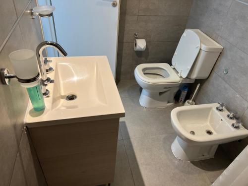 ein Badezimmer mit einem weißen Waschbecken und einem WC in der Unterkunft Ninfas Plaza in Puerto Madryn