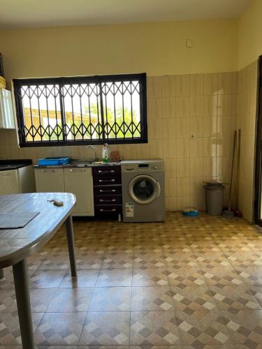 a kitchen with a washing machine and a table at CC House in Chidenguele