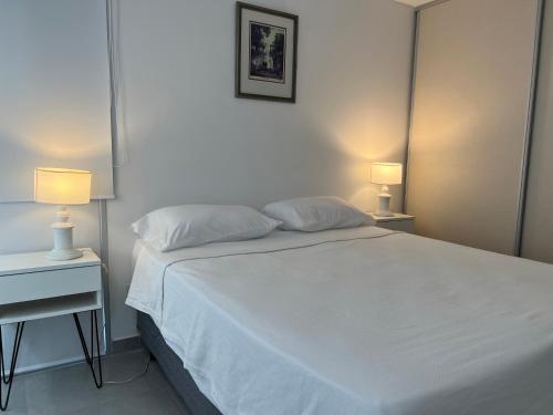 ein Schlafzimmer mit einem weißen Bett und zwei Lampen in der Unterkunft Ninfas Plaza in Puerto Madryn