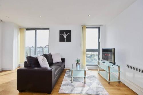 uma sala de estar com um sofá preto e uma televisão em Yorksha Luxury Apartments Leeds em Leeds