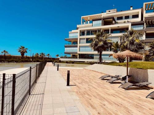 ein Gebäude mit Stühlen und Sonnenschirmen neben einem Strand in der Unterkunft OCEAN HOMES, Apartamentos exclusivos en Isla Canela - By AC REAL in Isla Canela
