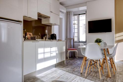 a kitchen with white cabinets and a table and chairs at Palacete da Baixa by MY CHOICE in Faro