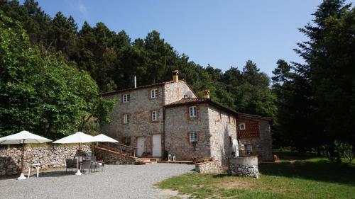 an old stone building with umbrellas in front of it at Agriturismo le Vallilunghe in Lucca