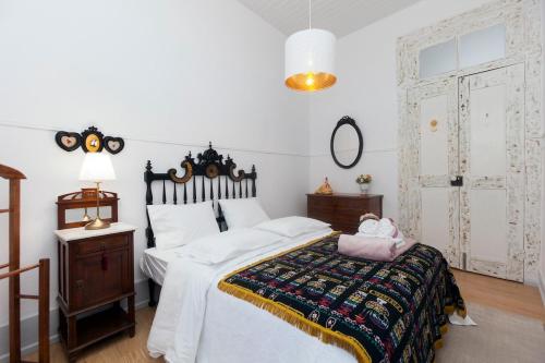 a bedroom with a large bed with white sheets and a table at Casa Dourada in Barcelos