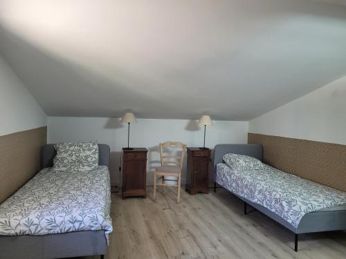 a room with two beds and a chair and a table at Gîte l'atelier de Phil et Delfe in Sainte-Cécile-les-Vignes