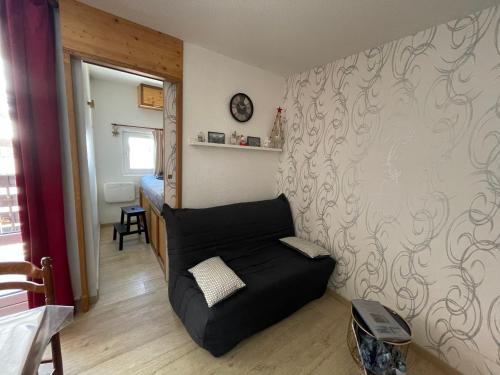 una sala de estar con un sofá negro en una habitación en Petit appartement confort Les 2 Alpes résidence Arc en Ciel télésiège Petite Aiguille, en Les Deux Alpes