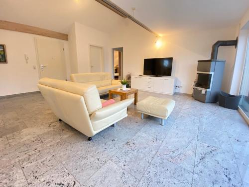 a living room with white furniture and a tv at 4 Zimmer Apartment, 125 qm, ruhig und zentrumsnah, max 5 Pers, Dachterasse, Garage, 1000 MBit in Böblingen