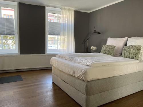 a bedroom with a large bed and two windows at Altstadt Fereienwohnung Hameln in Hameln
