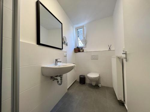 a white bathroom with a sink and a toilet at Altstadt Fereienwohnung Hameln in Hameln