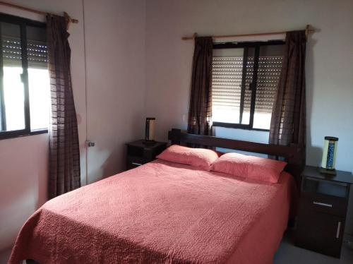 1 dormitorio con 1 cama con sábanas rosas y ventanas en Novgorod, en Aguas Dulces