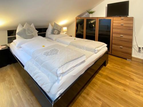 a large bed in a bedroom with a dresser at 4 Zimmer Apartment, 125 qm, ruhig und zentrumsnah, max 5 Pers, Dachterasse, Garage, 1000 MBit in Böblingen