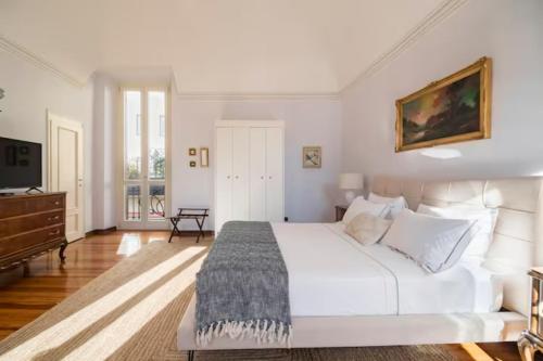 a bedroom with a large white bed and a television at Large, luxurious family apartment in Biella's historic center in Biella