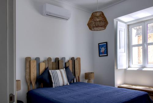 a bedroom with a blue bed and a window at Apartamentos do Rio in Tavira