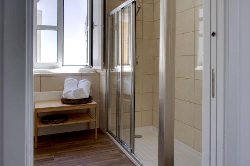 a shower with a glass door in a bathroom at Apartamentos do Rio in Tavira