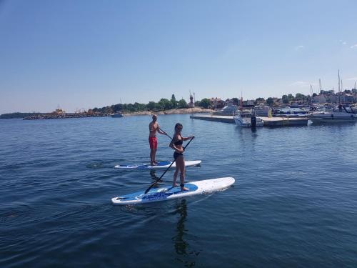 a man and a woman on a paddle board in the water at Epokgården in Öregrund