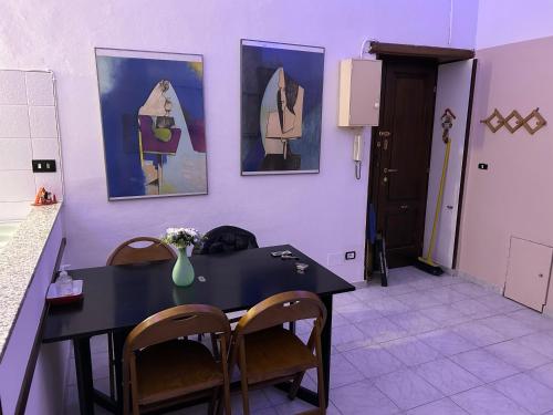 a dining room with a table and chairs and paintings at Luminoso Monolocale zona servita in Legnano
