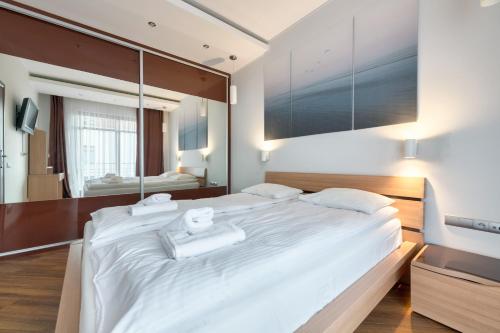 a bedroom with a large white bed and a large mirror at Dom & House - Apartment Neptun Park Premium in Jelitkowo