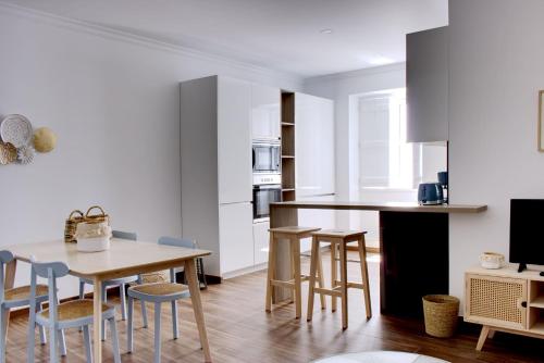 a kitchen with a wooden table and some chairs at Apartamentos do Rio in Tavira