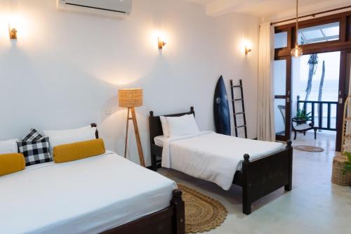 1 dormitorio con 2 camas y balcón en Surf Station, en Ahangama