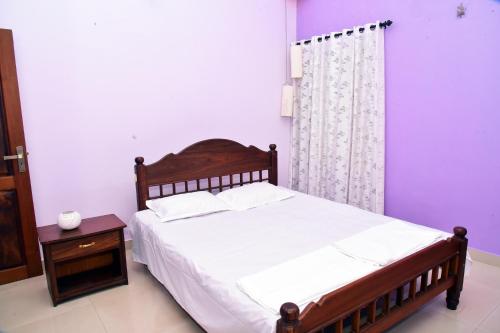 a bedroom with a large bed and a night stand at Bella Apartments in Tellicherry