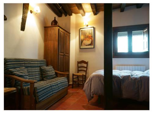 ein Schlafzimmer mit einem Bett, einem Sofa und einem Stuhl in der Unterkunft Apartamentos Rurales Víctor Chamorro del Arco in Hervás