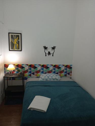 a bedroom with a bed with a green blanket and a table at Vilarejo Hostel Pinheiros Guest House in Sao Paulo