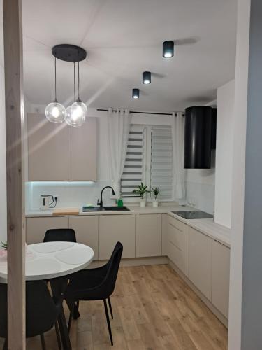 cocina con armarios blancos, mesa y sillas en Apartament Komfort, en Słupsk