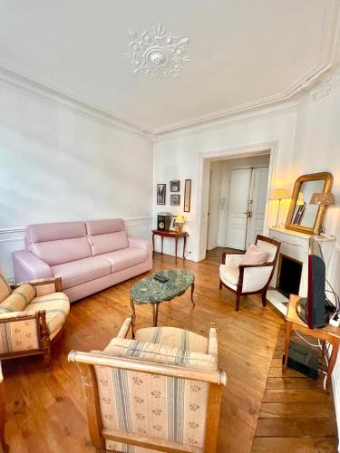 uma sala de estar com um sofá rosa e uma mesa em BASSANO em Paris