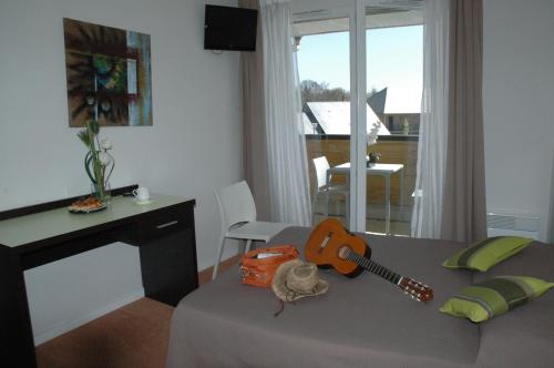 a room with a bed with a guitar on it at Adonis Hauts De Honfleur in Équemauville