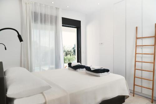 a white bedroom with a bed and a window at Villa Mouria private seaview villa in Pogoniá