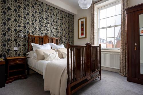 a bedroom with a bed and a wall covered in wallpaper at St Johns House Lichfield in Lichfield